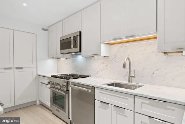 a kitchen with stainless steel appliances granite countertop white cabinets and a stove top oven