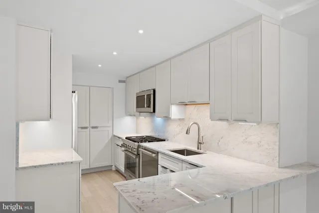 a kitchen with stainless steel appliances kitchen island granite countertop a sink and a refrigerator