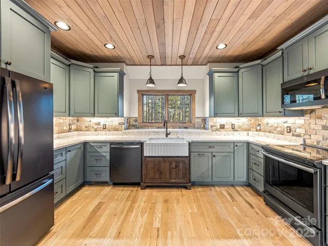a large kitchen with a large window a sink stainless steel appliances and cabinets