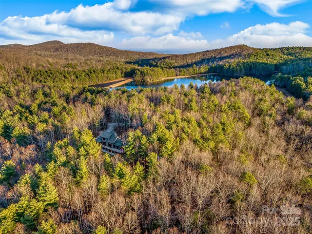 a view of a wooden house with large trees and wooden fence