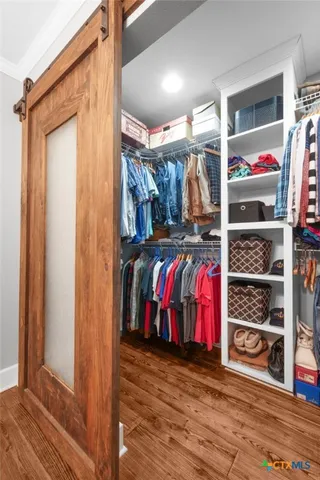 a view of walk in closet with clothes and shoes