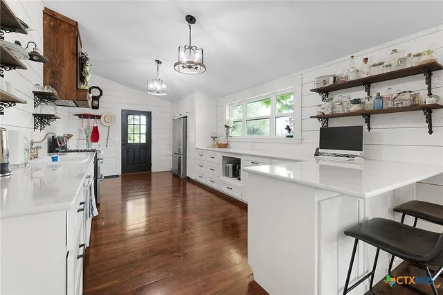 a kitchen with stainless steel appliances a stove top oven a sink a dining table and chairs with wooden floor