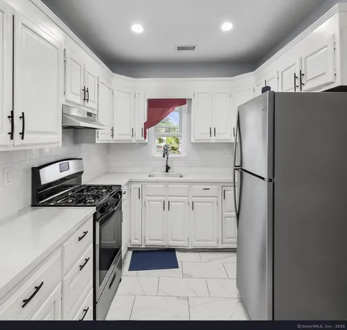 a kitchen with stainless steel appliances granite countertop a refrigerator sink and stove