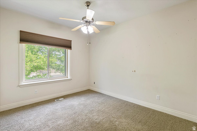 316 Azure Circle Draper, UT 84020 - Photo 24 of 48 Spacious room featuring a large window with exterior landscaping, neutral wall tones, a ceiling fan with integrated lighting, and plush carpet flooring