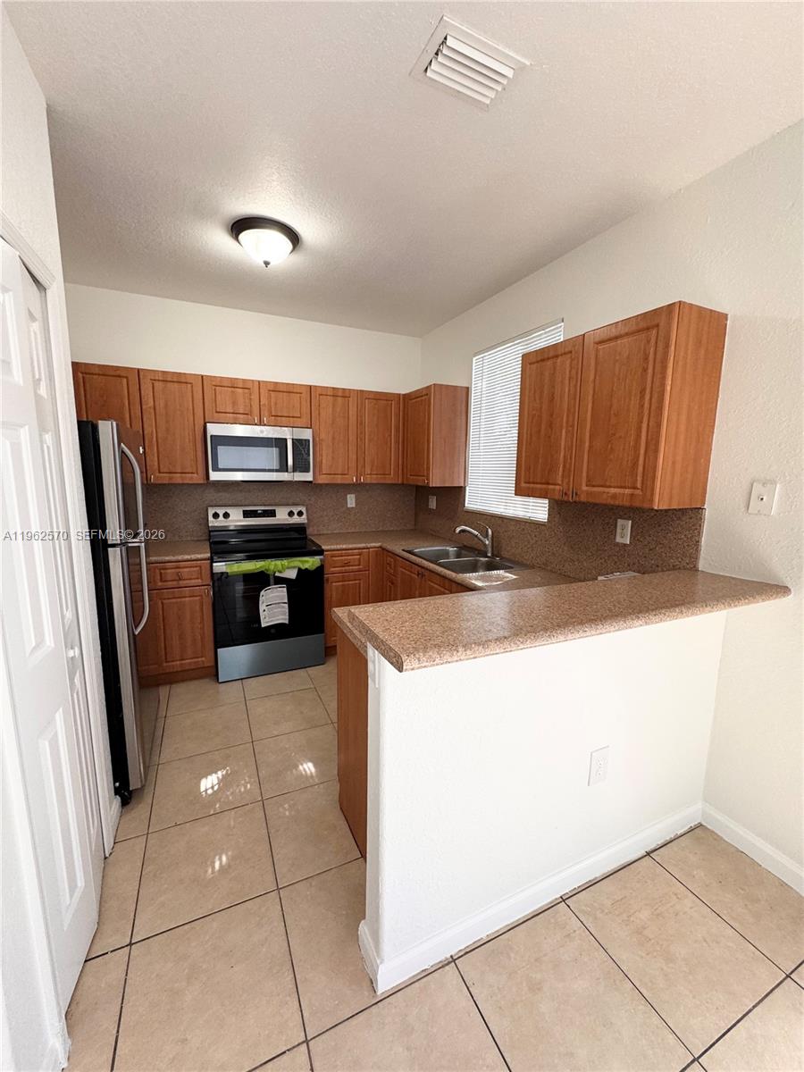 2732 Southeast 15th Place, Unit 142 Homestead, FL 33035 - Photo 9 of 20 a kitchen with stainless steel appliances granite countertop a refrigerator and a stove top oven