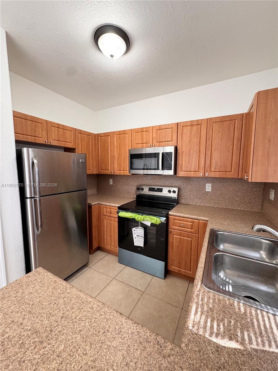 2732 Southeast 15th Place, Unit 142 Homestead, FL 33035 - Photo 10 of 20 a kitchen with stainless steel appliances granite countertop a refrigerator a stove a sink and a microwave