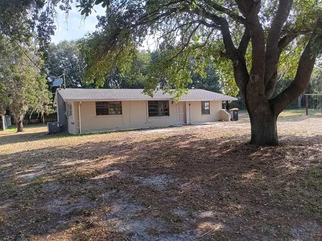 a front view of a house with a yard and large trees