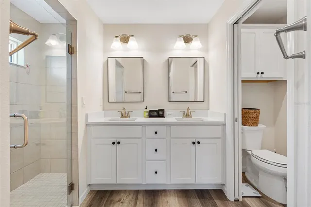 a spacious bathroom with a double vanity sink a toilet and a mirror