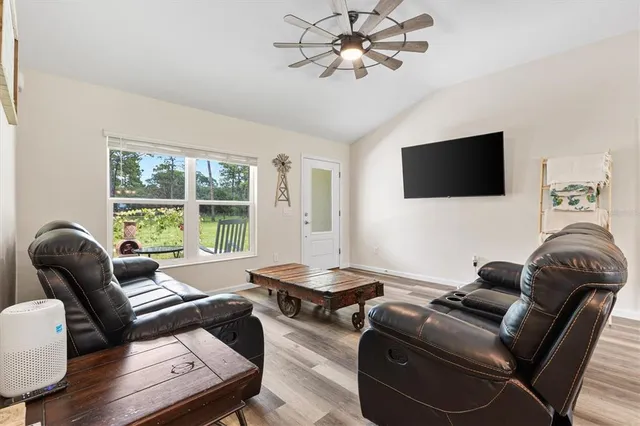 a living room with furniture a flat screen tv and a large window