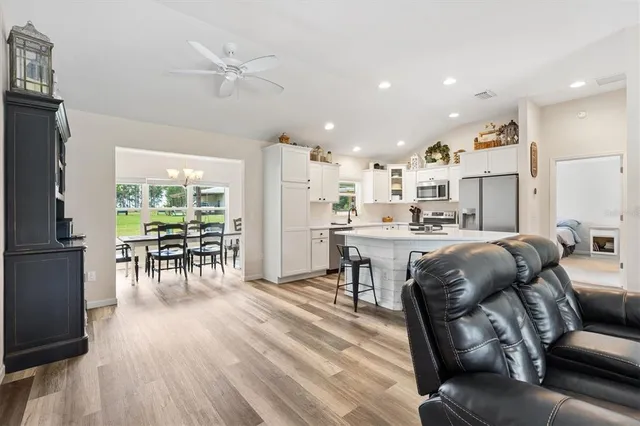 a living room with furniture and kitchen view with wooden floor