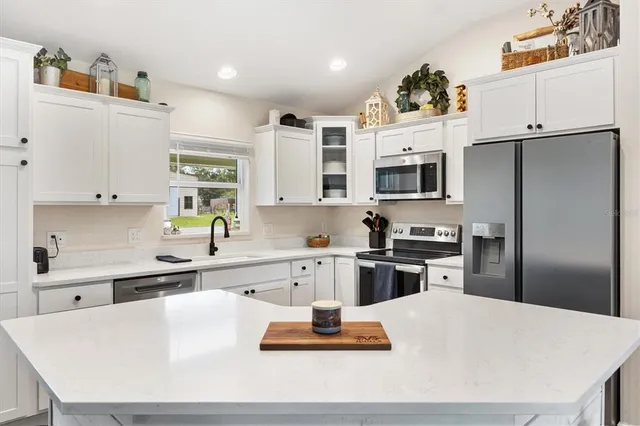 a kitchen with stainless steel appliances a stove a sink a microwave a refrigerator and cabinets
