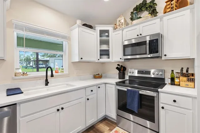 a kitchen with stainless steel appliances granite countertop white cabinets a stove a sink and a microwave