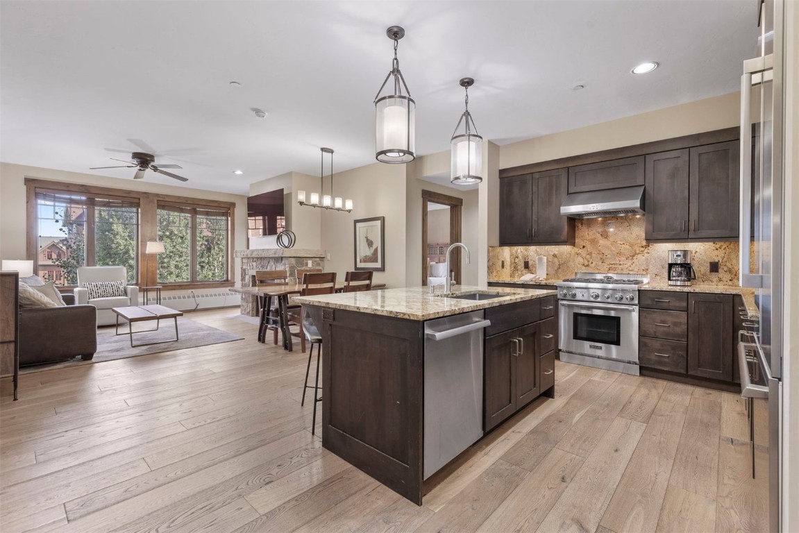 610 Columbine Road, Unit 6307 Breckenridge, CO 80424 - Photo 8 of 36 a kitchen with stainless steel appliances granite countertop wooden cabinets a sink dishwasher a stove and a dining table with wooden floor