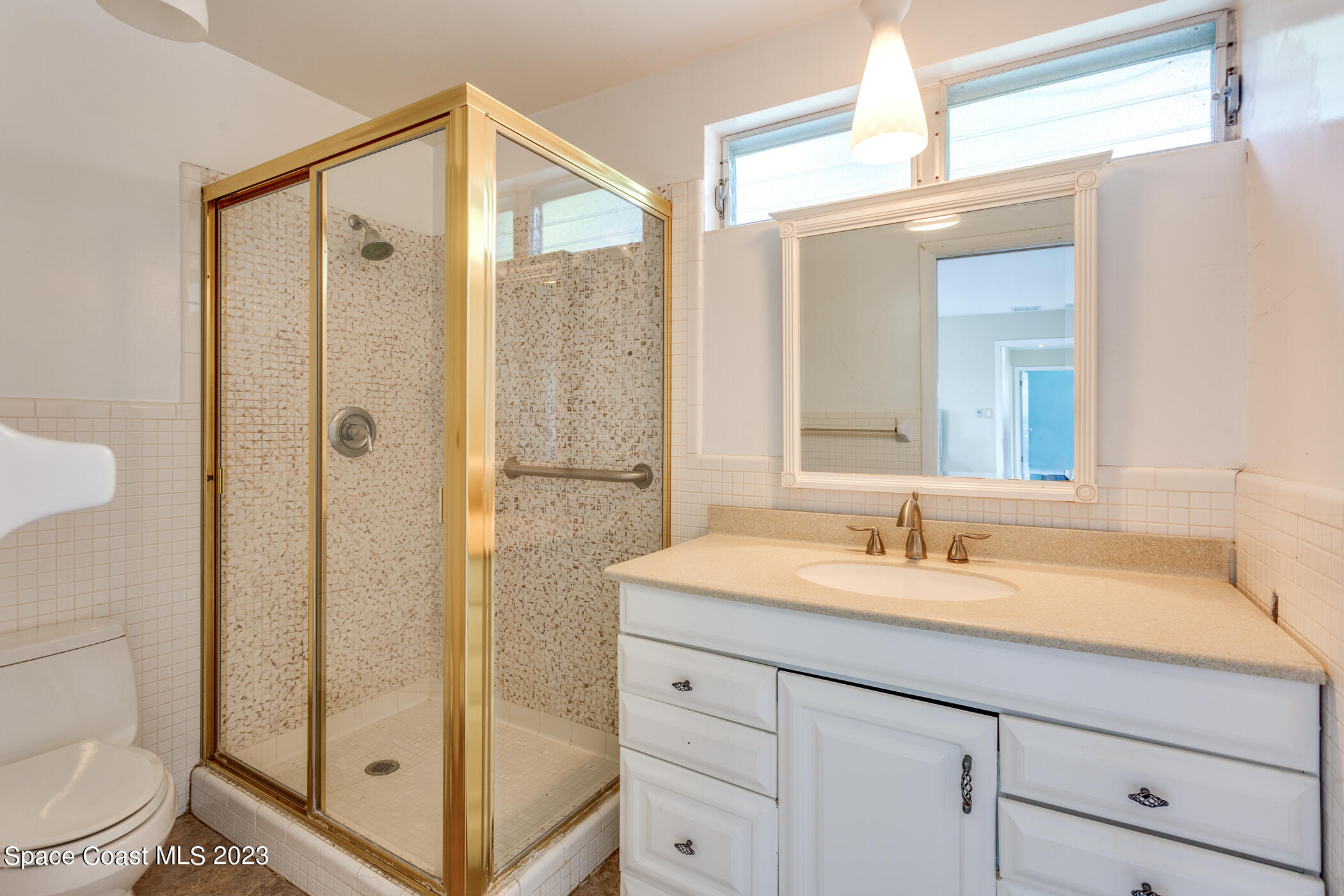 608 Mango Drive Melbourne Beach, FL 32951 - Photo 17 of 30 a bathroom with a shower sink vanity mirror and toilet