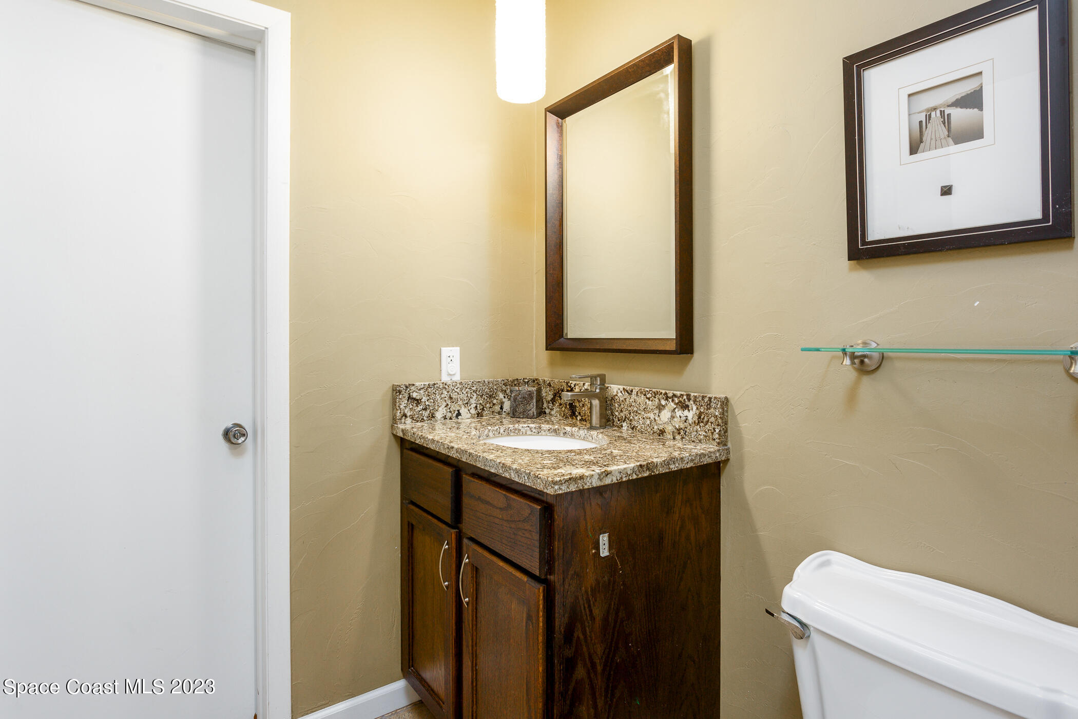 608 Mango Drive Melbourne Beach, FL 32951 - Photo 19 of 30 a bathroom with a granite countertop sink a toilet and mirror