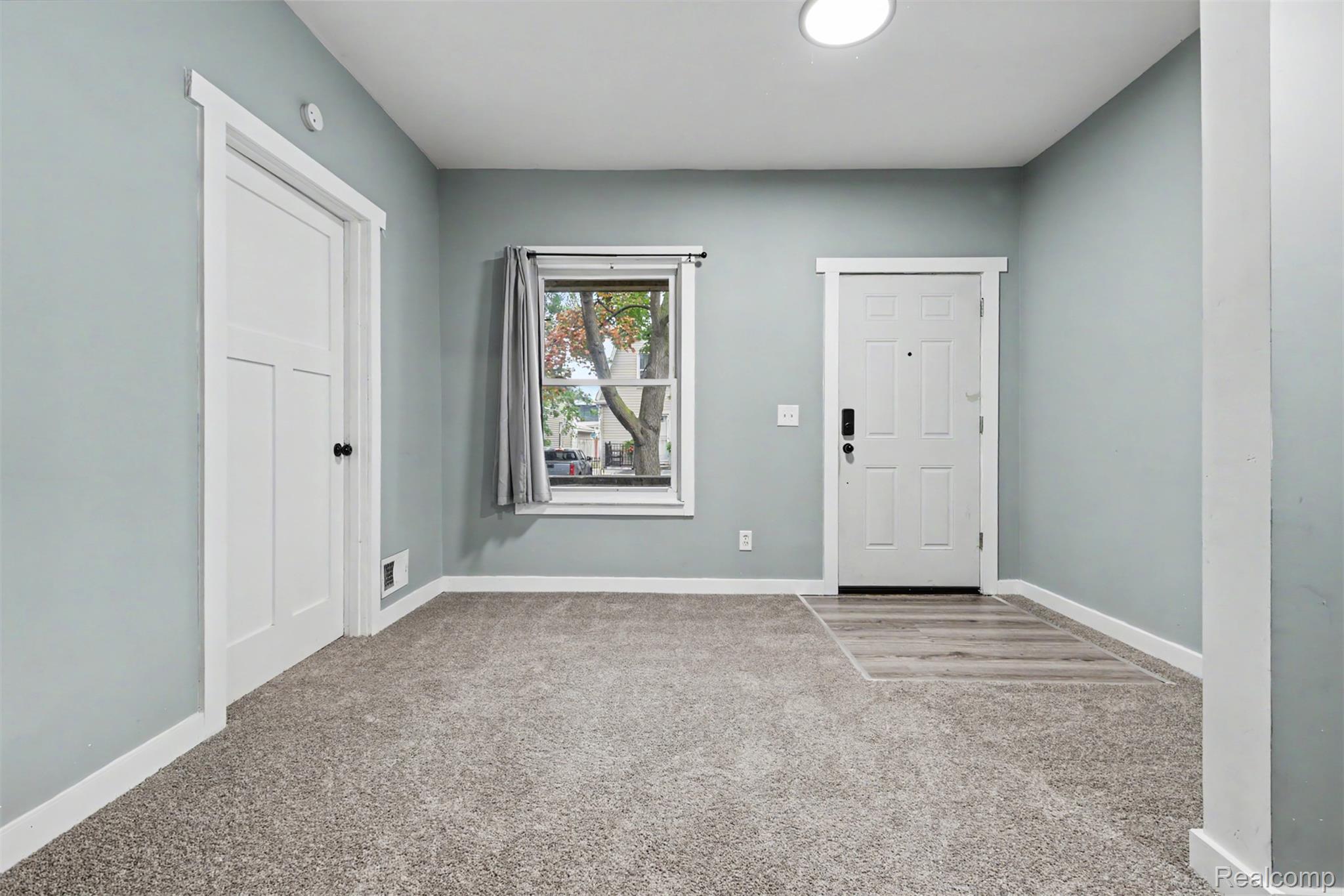 8397 Lane Street Detroit, MI 48209 - Photo 4 of 41 Bright entryway showcasing soft sage-green walls, neutral carpet flooring, and abundant natural light from a front-facing window