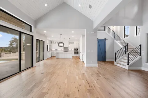 a view of a hallway with wooden floor and a kitchen