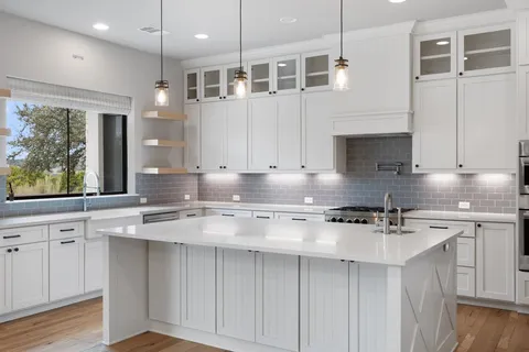 a kitchen with stainless steel appliances granite countertop a stove a sink and white cabinets