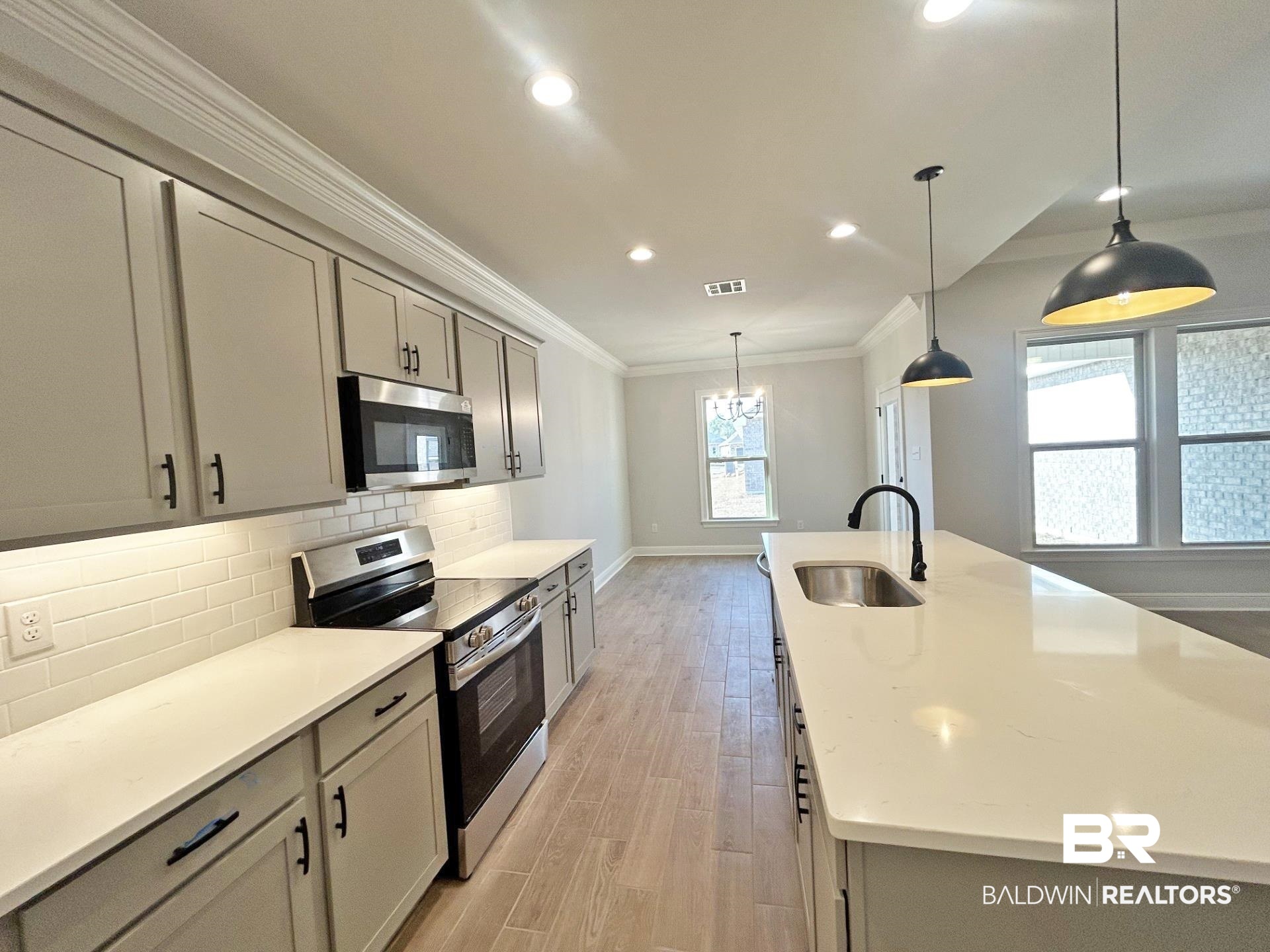825 Sumter Loop Foley, AL 36535 - Photo 4 of 21 Kitchen featuring appliances with stainless steel finishes, ornamental molding, pendant lighting, an island with sink, and light stone counters