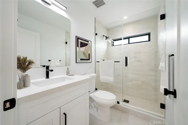 a bathroom with a shower sink vanity mirror and toilet