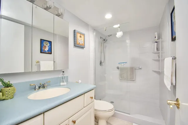 a bathroom with a granite countertop sink toilet a mirror and shower
