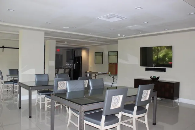 a dining hall with stainless steel appliances kitchen island granite countertop a table and chairs