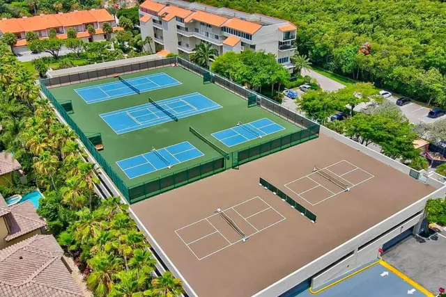 an aerial view of a tennis ground with a white house