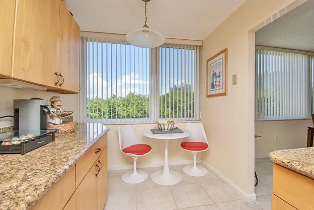 a kitchen with stainless steel appliances granite countertop a sink a stove a dining table and chairs