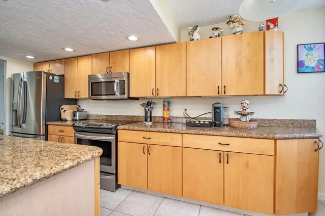 a kitchen with stainless steel appliances granite countertop a stove a sink and a refrigerator