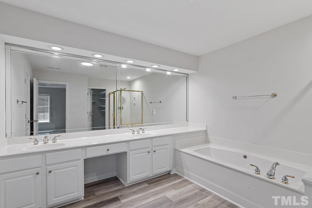 3914 Sunset Maple Court Raleigh, NC 27612 - Photo 17 of 30 a bathroom with a double vanity sink a large mirror and a bathtub