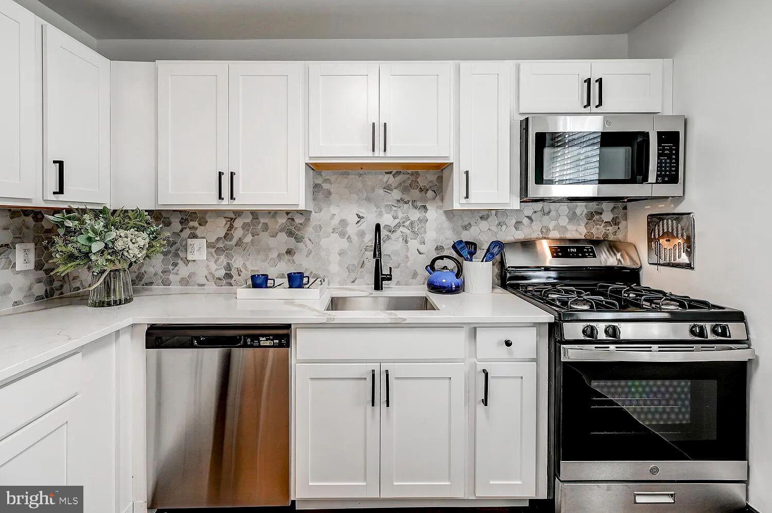a kitchen with white cabinets and appliances