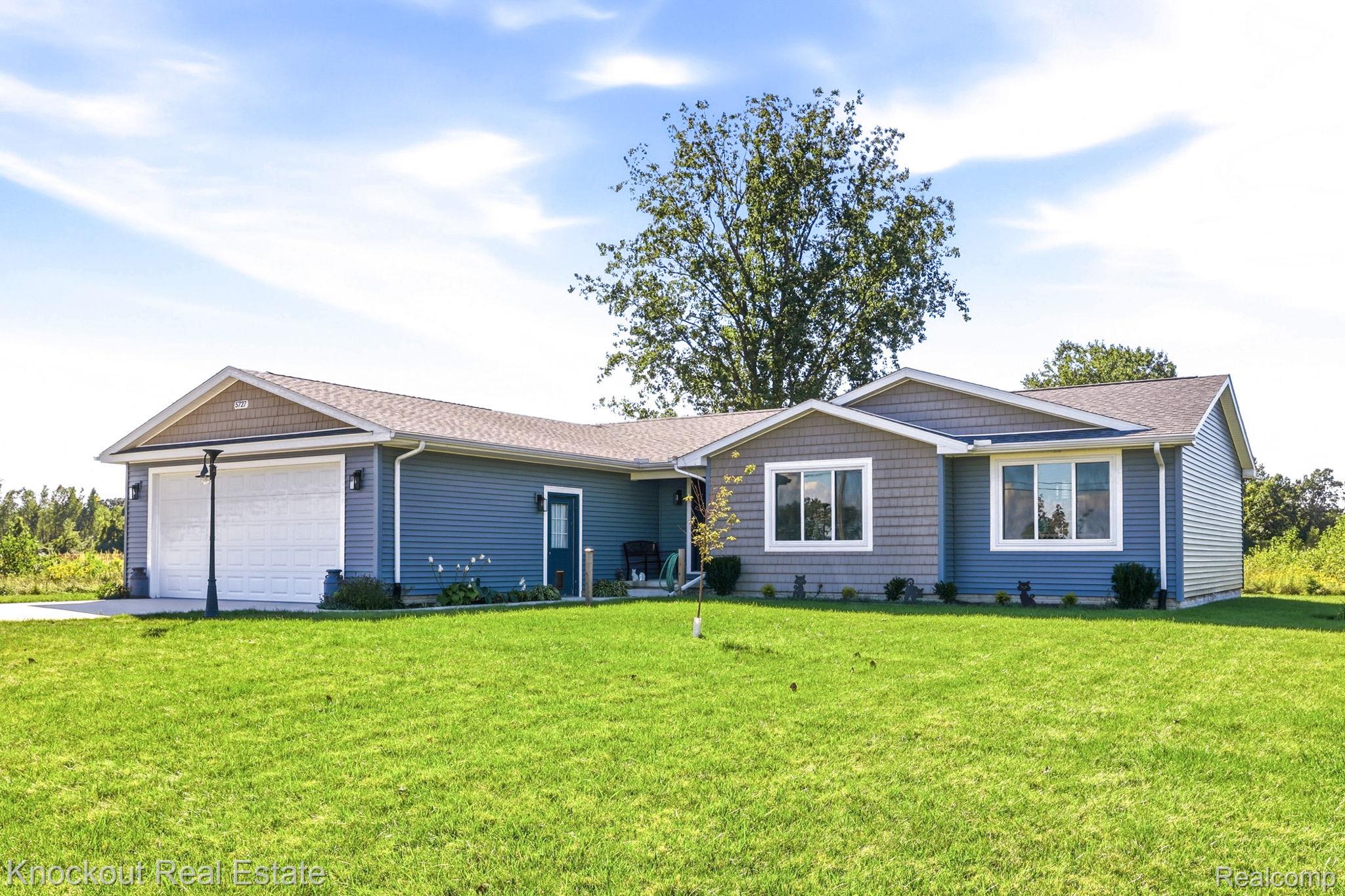 5727 Mackinaw Road Saginaw, MI 48604 - Photo 1 of 60 Expansive lawn with a two-car garage, blue siding, gray shake siding, and white-framed windows