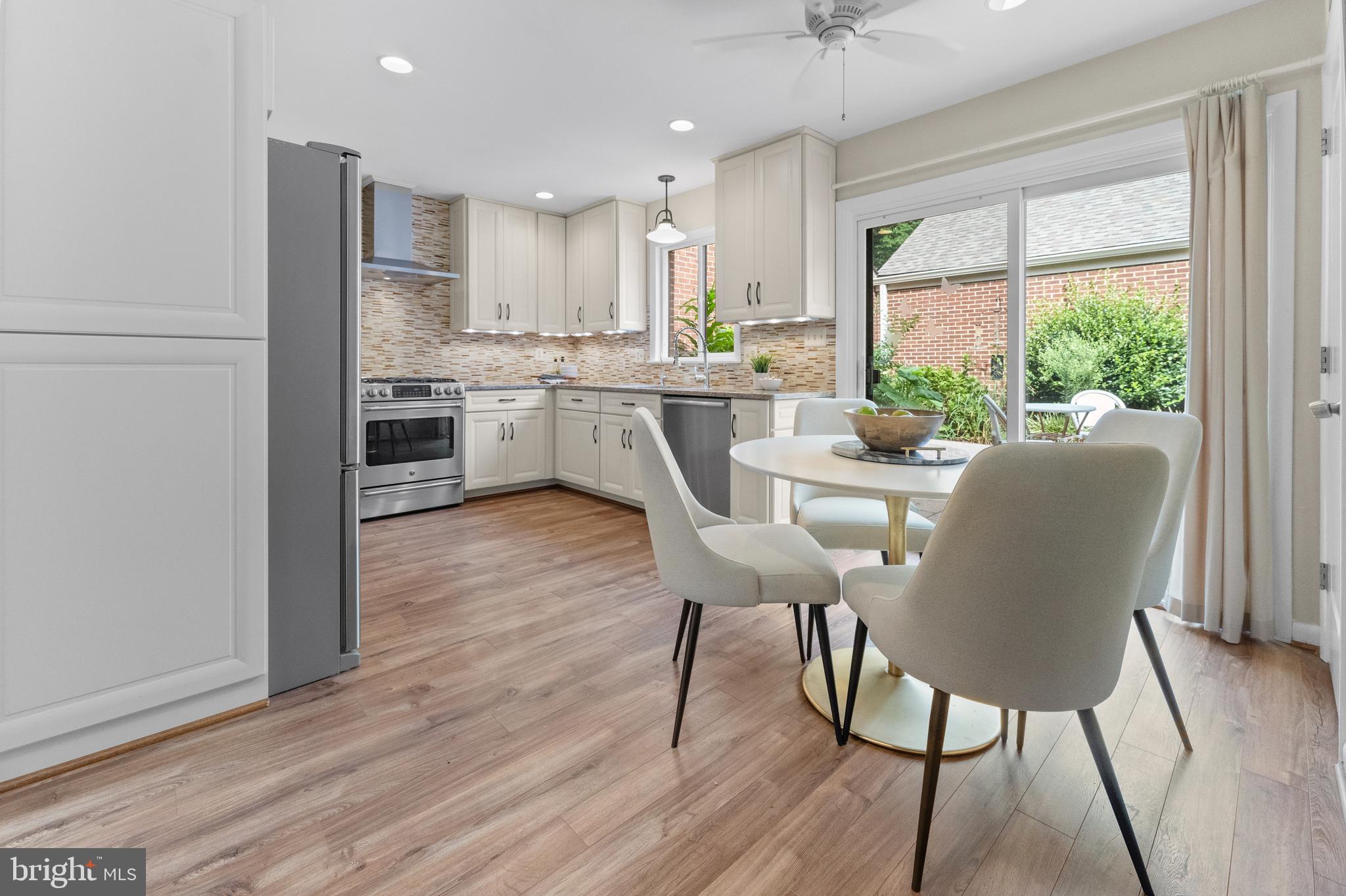 11303 Harborside Cluster Reston, VA 20191 - Photo 16 of 30 a kitchen with stainless steel appliances granite countertop a table chairs wooden floors a large window and white cabinets