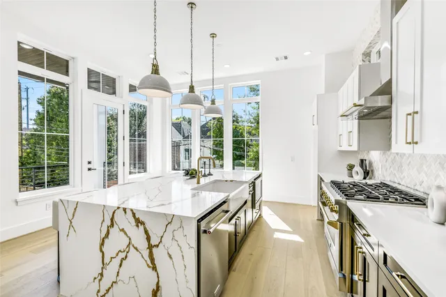 a kitchen with a stove a sink a counter top space and living room view