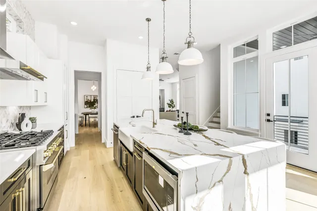 a large kitchen with kitchen island a stove a table a sink and cabinets