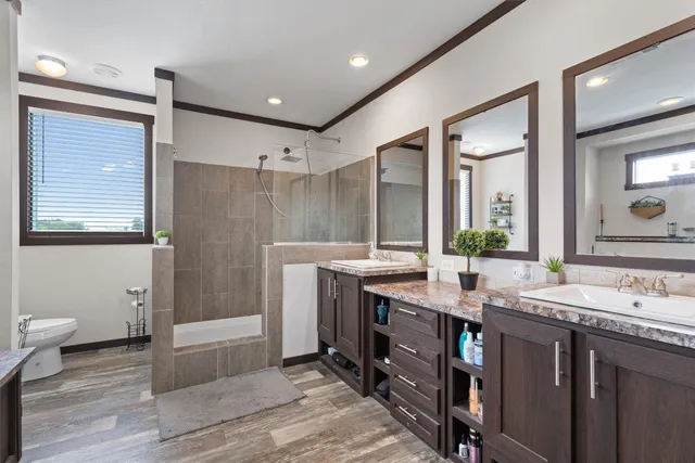 a bathroom with a granite countertop sink a toilet a mirror and shower