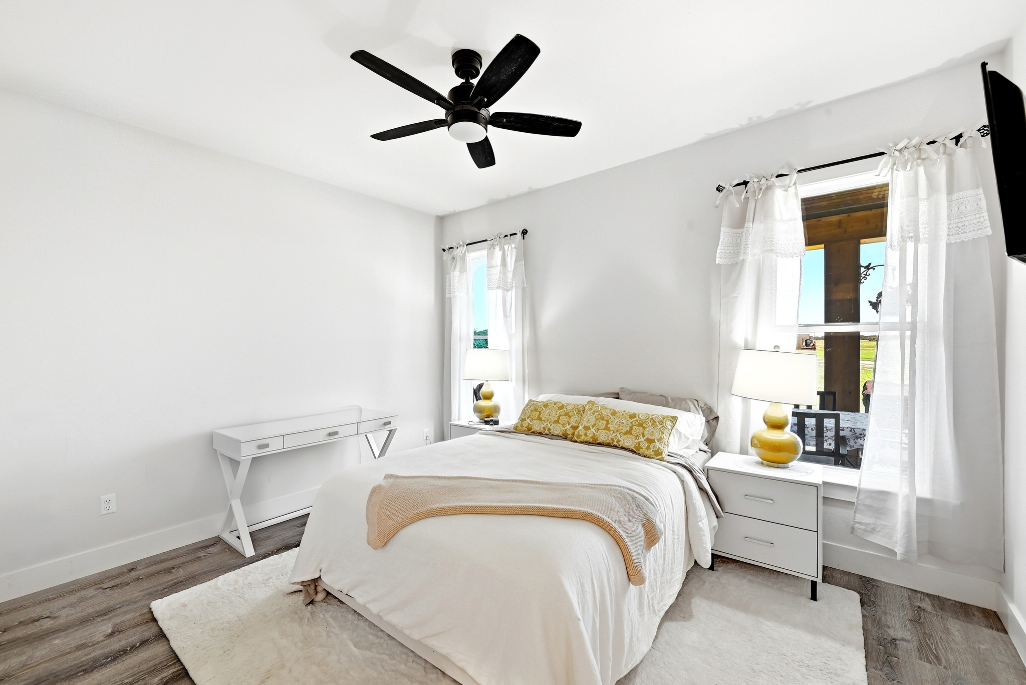 2889 Old McMahan Road Lockhart, TX 78644 - Photo 24 of 33 A well-lit bedroom features hardwood flooring, white walls, and a prominent ceiling fan.