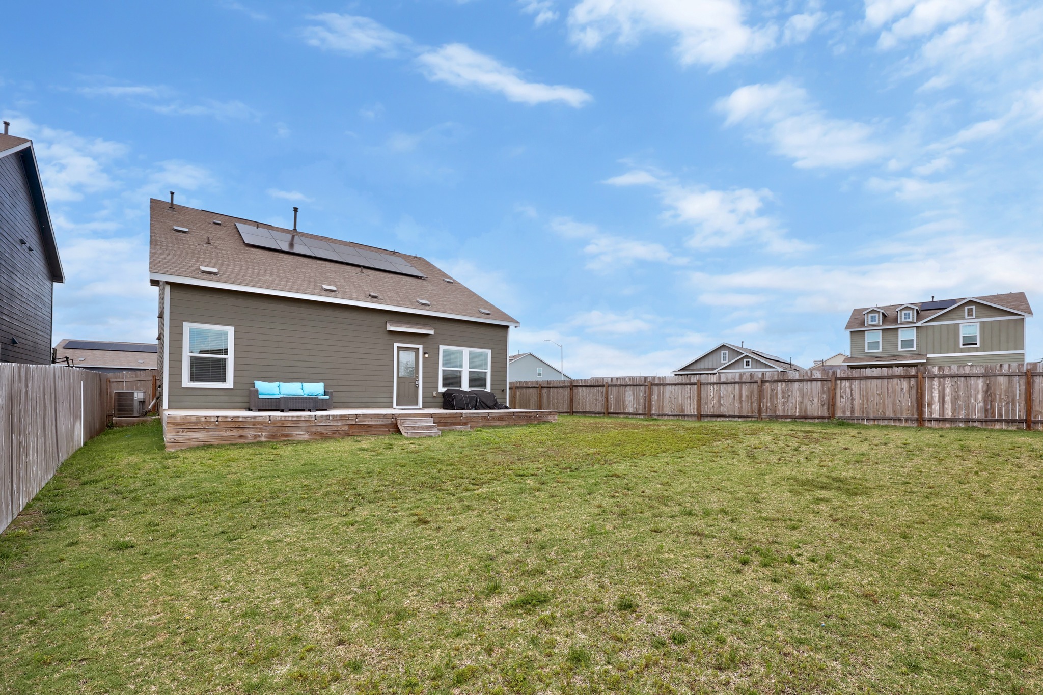 14121 Berning Road Manor, TX 78653 - Photo 22 of 27 A spacious yard extends beyond a home with a wooden deck, perfect for outdoor living.
