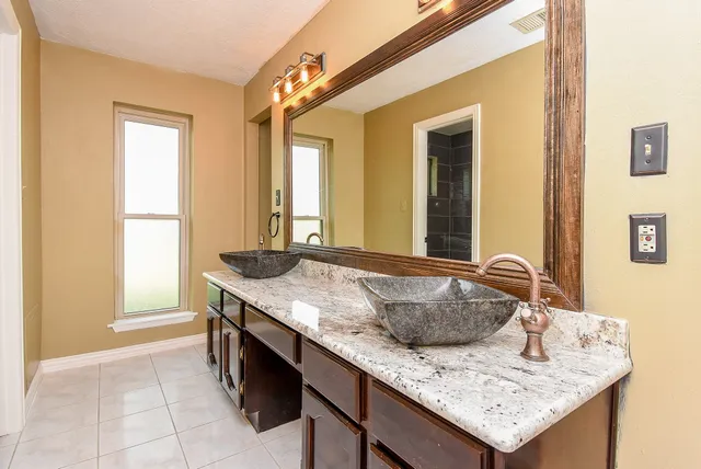 a bathroom with a granite countertop sink and a mirror