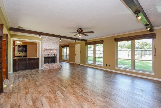 a view of empty room with wooden floor and a window