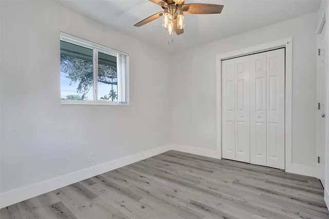 a view of an empty room with wooden floor and a ceiling fan