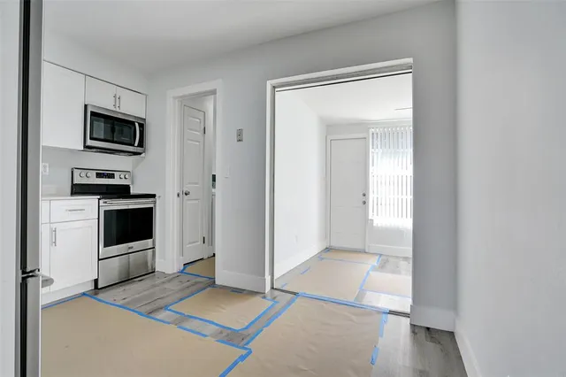 a view of a kitchen with wooden floor electronic appliances and bedroom