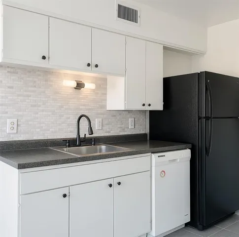 a kitchen with granite countertop white cabinets and refrigerator