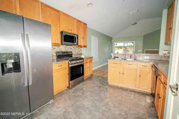a kitchen with stainless steel appliances granite countertop a stove top oven a sink and a refrigerator