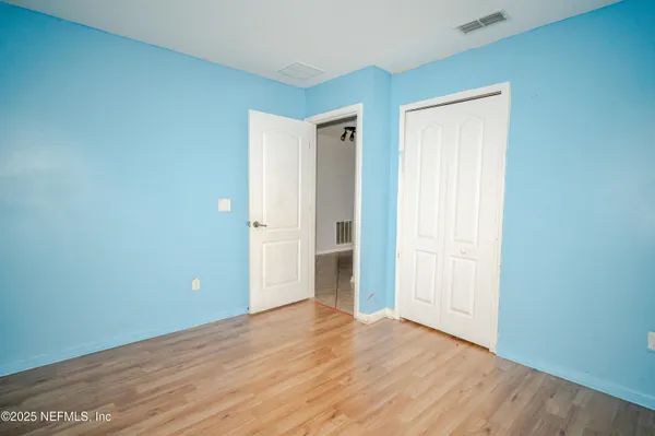 a view of an empty room with wooden floor and closet