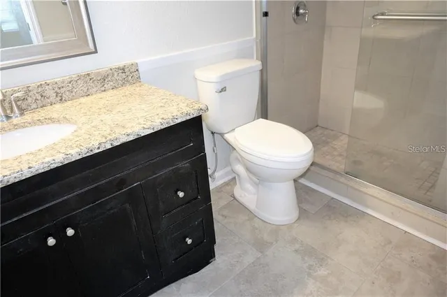 a bathroom with a granite countertop sink and a toilet