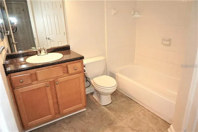 a bathroom with a granite countertop toilet sink and mirror