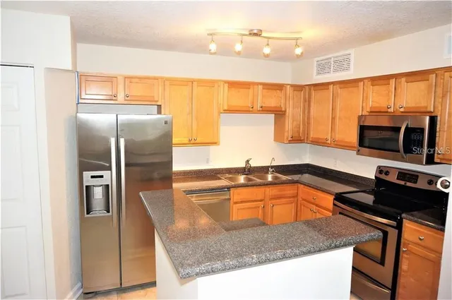 a kitchen with stainless steel appliances granite countertop a sink a stove and a refrigerator