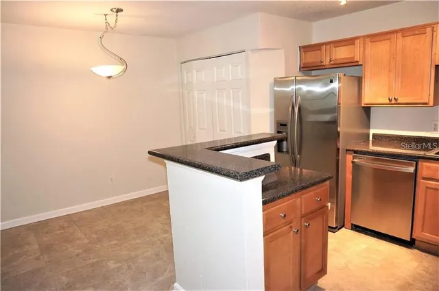 a kitchen with stainless steel appliances granite countertop a refrigerator a sink dishwasher a stove with wooden cabinets