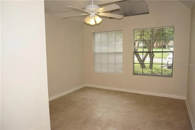 an empty room with windows and fan